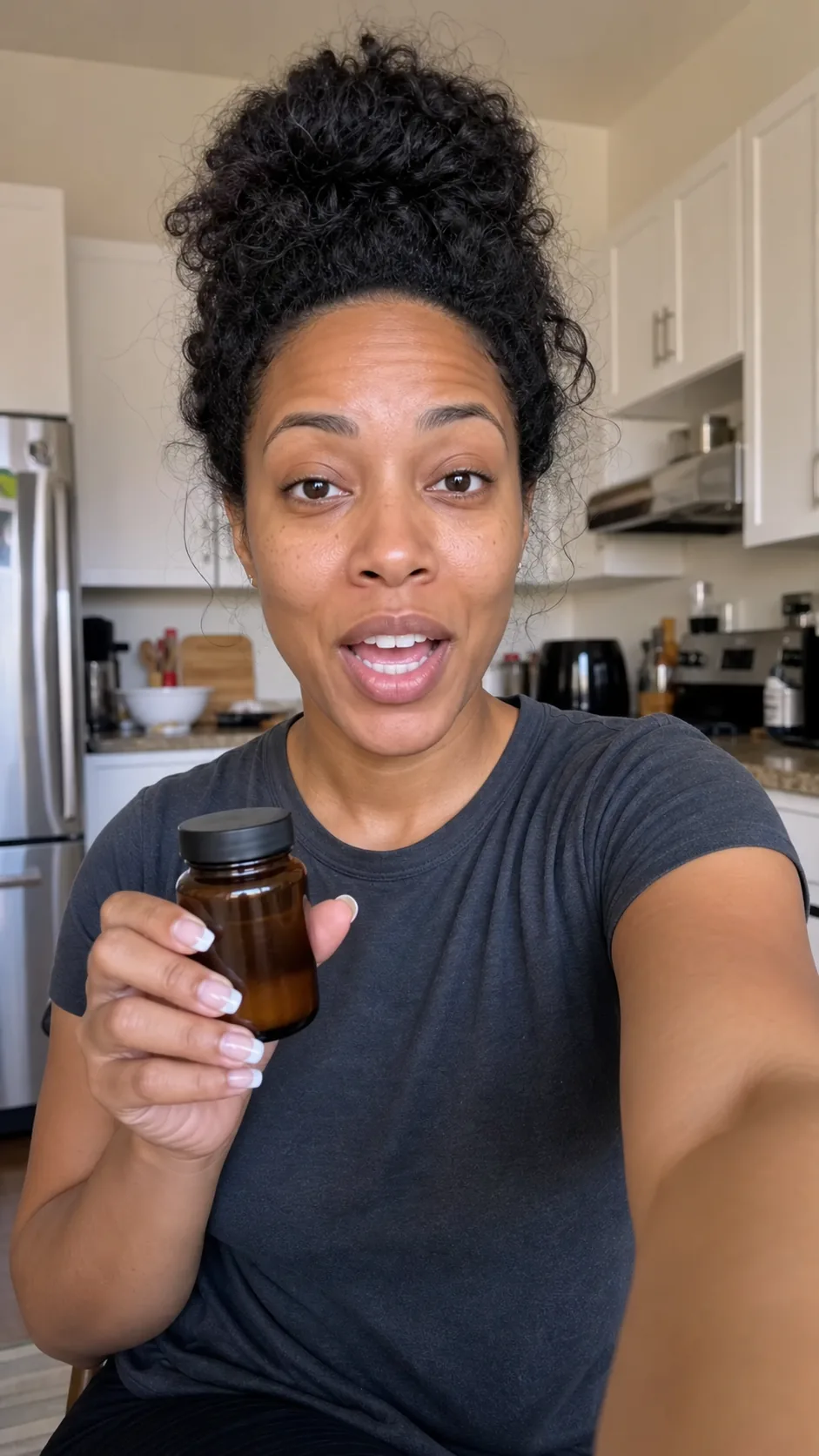 Woman films a kitchen selfie while holding an unbranded amber supplement bottle.